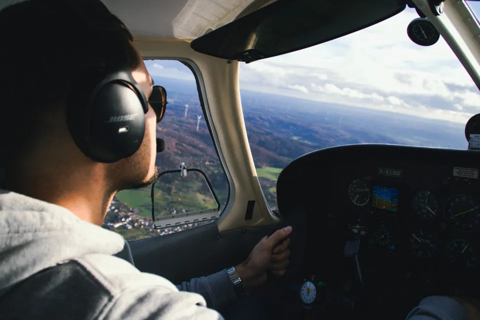 Pilot mit Headset im Flug über Windrädern